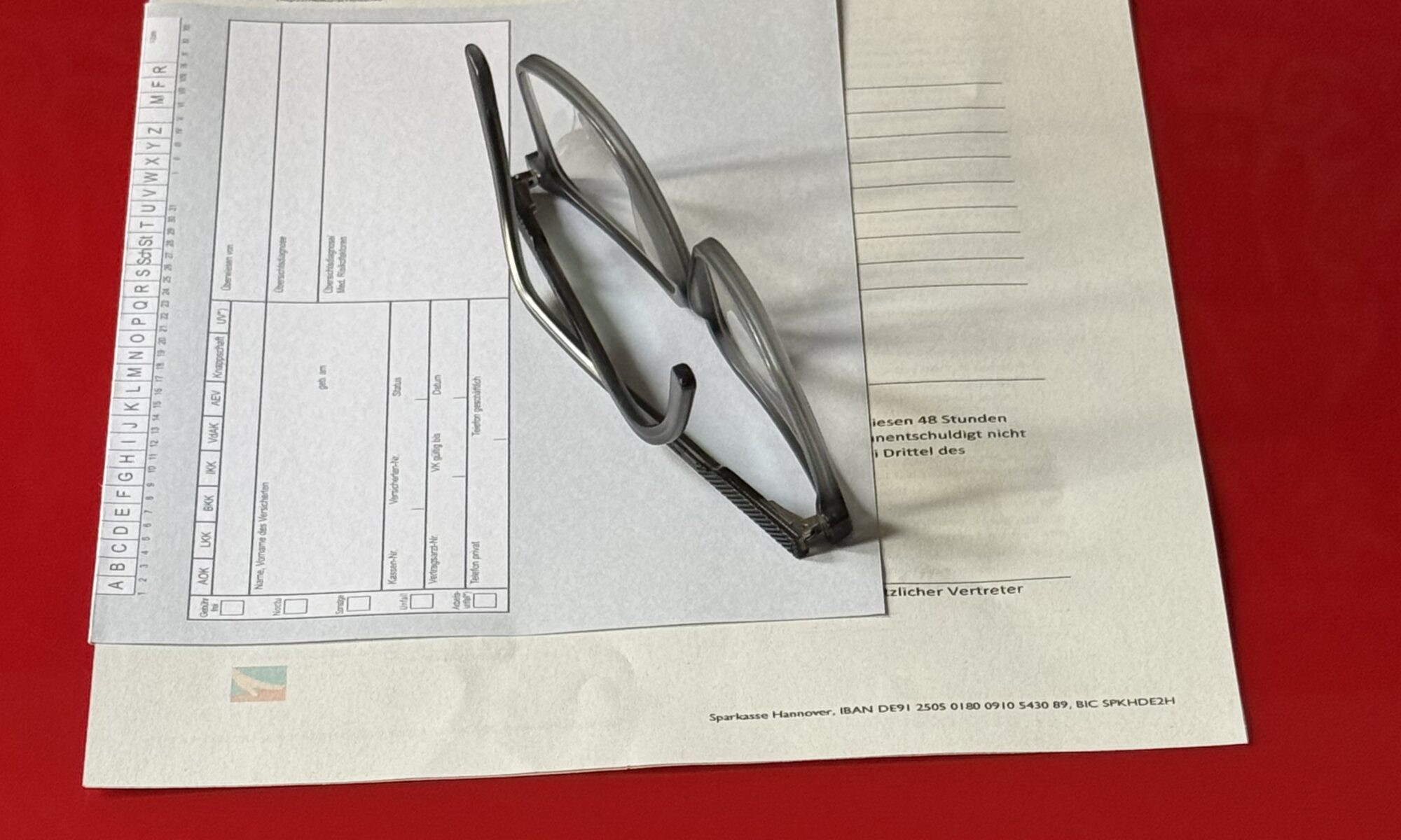 Brille liegt auf Anmeldeunterlagen und Karteikarte
