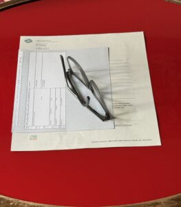 Brille liegt auf Anmeldeunterlagen und Karteikarte